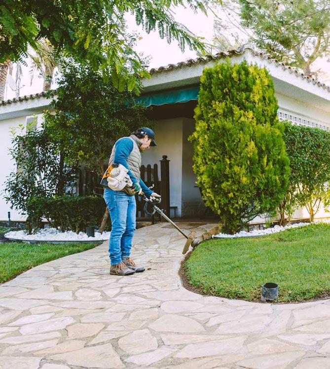 Trabajador de Gartalia cortando el césped en Resort El Oasis La Eliana